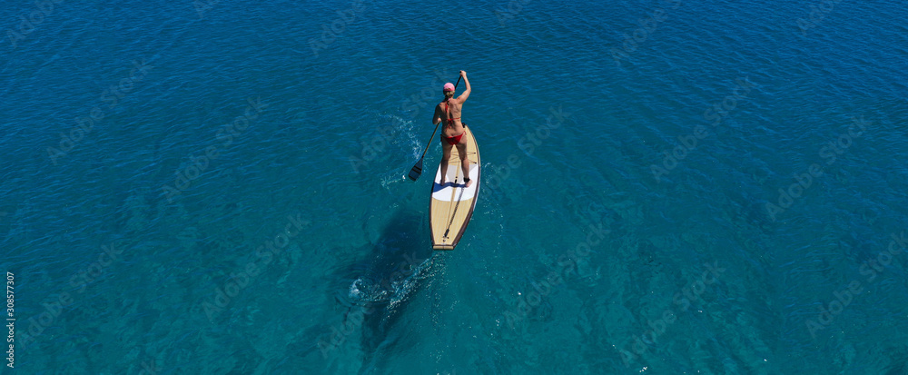 Fototapeta premium Aerial drone ultra wide panoramic photo of unidentified fit woman practising in Stand Up Paddle board or SUP in tropical island exotic turquoise bay