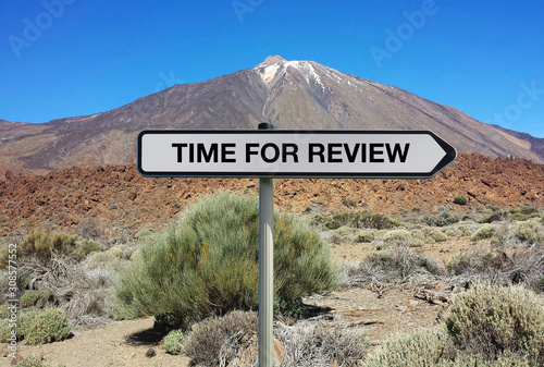 Road sign with TIME FOR REVIEW text under volcano background