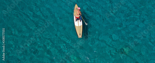 Aerial drone ultra wide panoramic photo of unidentified fit woman practising in Stand Up Paddle board or SUP in tropical island exotic turquoise bay
