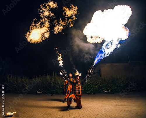 Fire show, dancing with flame, male master fakir with fire works, performance outdoors, flame control man, a man in a suit LED dances with fire, draws a fiery figure in the dark photo