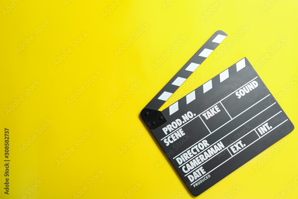 Clapper board on yellow background, top view with space for text. Cinema production