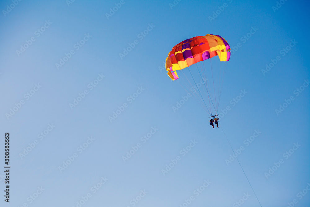 Couple under parachute hanging mid air. Having fun. Tropical Paradise. Positive human emotions, feelings, family, travel, vacation. Tourism day. Copy space Couple under parachute hanging mid air. Having fun. Tropical Paradise. Positive human emotions, feelings, family, travel, vacation. Tourism day. Copy space