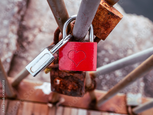 Red love lock with heart symbol, locked on a bridge rail