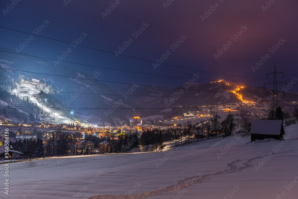 Late evening, night mountains landscape of a popular ski resort in Austrian Alps. A illuminated ski slope, night skiing and snow mountains as background. Schladming, Steiermark, Austria.