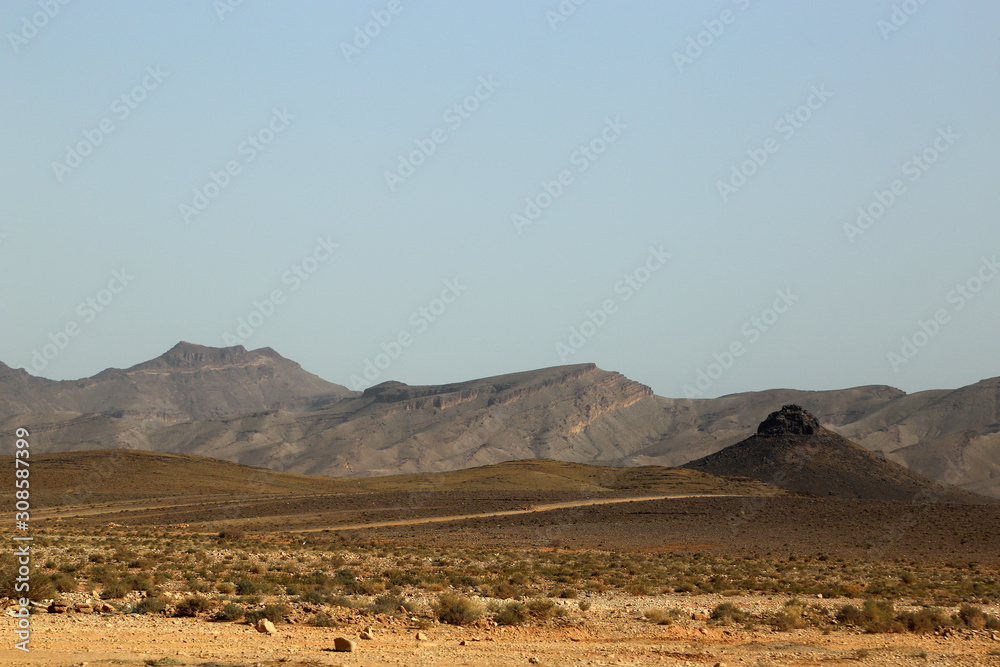 A desolate landscape with a mountain range in the background along the road from Ouarzazate to Fez in Marroko.