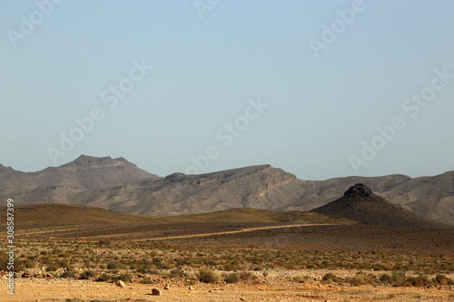 A desolate landscape with a mountain range in the background along the road from Ouarzazate to Fez in Marroko.