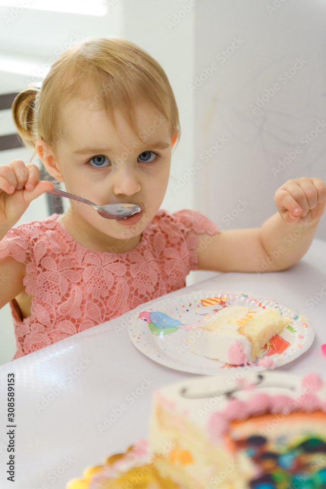 Baby girl 1 year old eating birthday cake in room. Birthday party. Childhood Baby girl 1 year old eating birthday cake in room. Birthday party. Childhood
