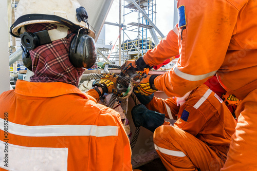 A team of rigger preparing the sling for heavy lift of a structure frame from a construction work barge onto a oil production platform at oil field
