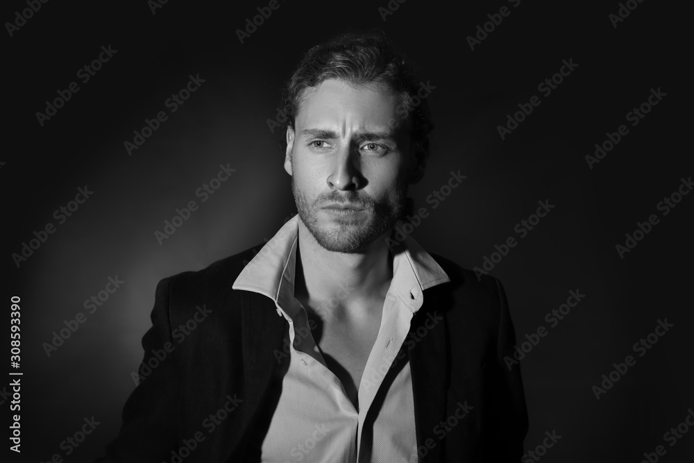 Fototapeta premium Black and white portrait of handsome businessman on dark background