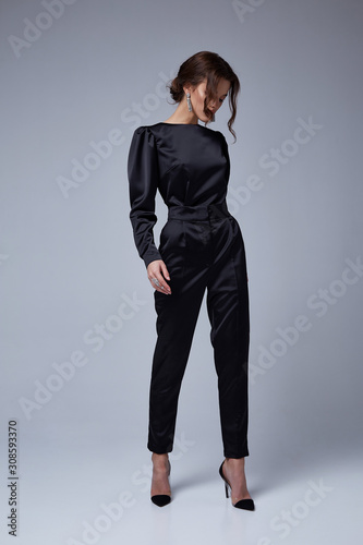 Beautiful sexy young business woman brunette hair evening makeup wearing dress black suit jacket trousers high heels shoes business clothes for meetings walks fall collection perfect body shape.