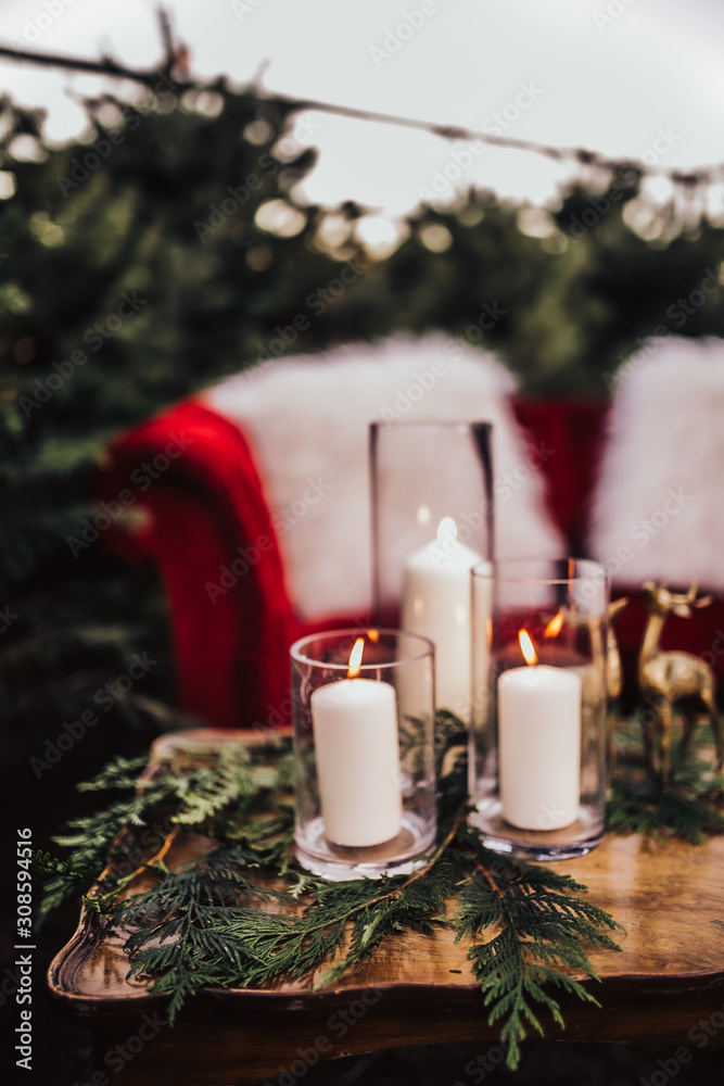 Christmas styled wooden table with candles and tree branches. Red velvet couch in the background. Concept of design and winter decorations. Christmas styled wooden table with candles and tree branches. Red velvet couch in the background. Concept of design and winter decorations.