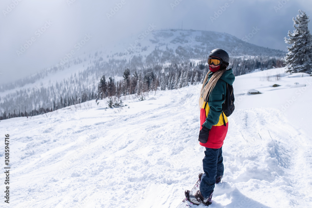 Young woman snowboarder goes to the Siberian mountains.