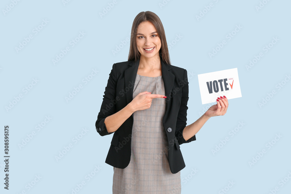 Young woman holding paper with text VOTE on color background Young woman holding paper with text VOTE on color background