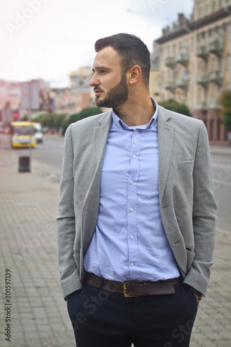 Portrait of a businessman on the street near the road of a European city. A bearded handsome man dressed stylishly. Fashionable guy hipster. Stock photos