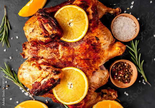 baked chicken or fried chicken with orange with spices on a stone background, top view, ready to eat