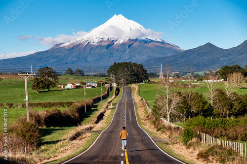 Determined person runs on a straight road toward snow mountain