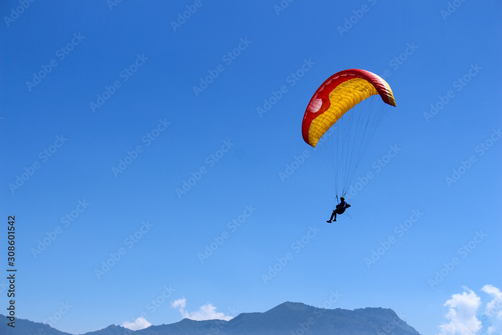 a paraglider flying in blue sky landscape in Indonesia a paraglider flying in blue sky landscape in Indonesia
