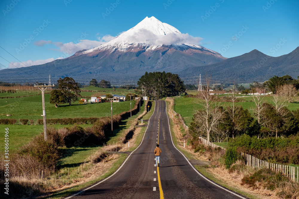 Fototapeta premium Determined person runs on a straight road toward snow mountain