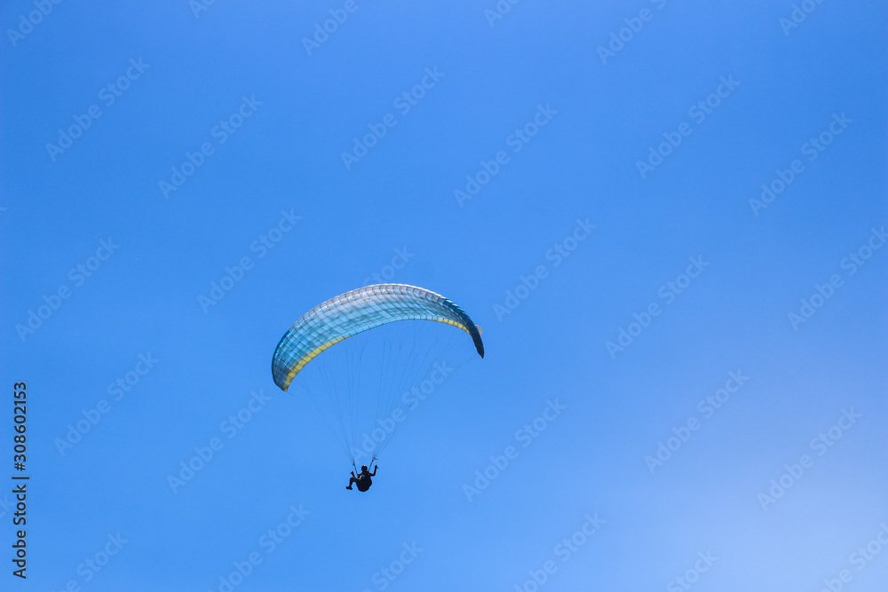 a paraglider flying in blue sky landscape in Indonesia a paraglider flying in blue sky landscape in Indonesia