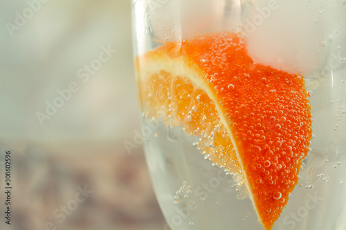 glass with oranges, ice, sparkling water close-up
