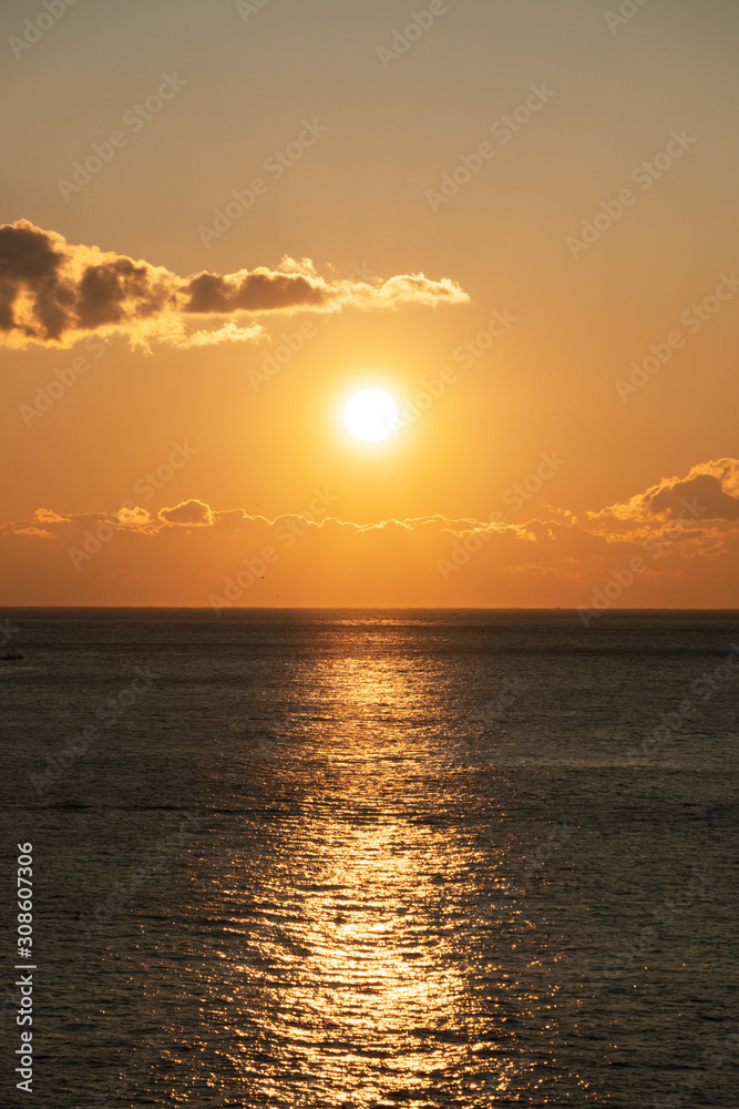 Fototapeta premium Bright sunset with large yellow sun under the sea surface.