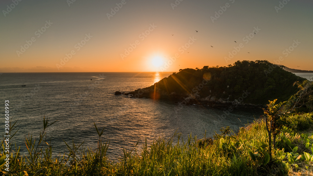 Obraz premium Pássaros voando com o sol nascendo nas montanhas sobre o mar