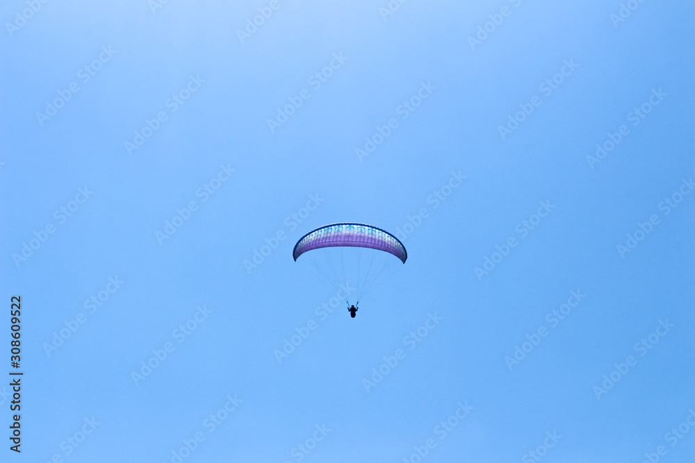 paraglider flying in blue sky on valleys landscape in Indonesia paraglider flying in blue sky on valleys landscape in Indonesia