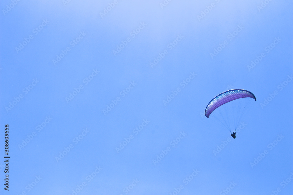 paraglider flying in blue sky on valleys landscape in Indonesia paraglider flying in blue sky on valleys landscape in Indonesia