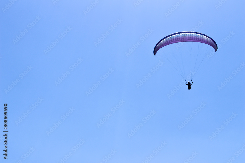 paraglider flying in blue sky on valleys landscape in Indonesia paraglider flying in blue sky on valleys landscape in Indonesia
