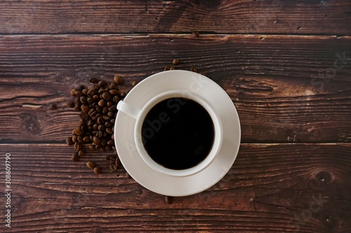 cup of coffee with beans on wooden table