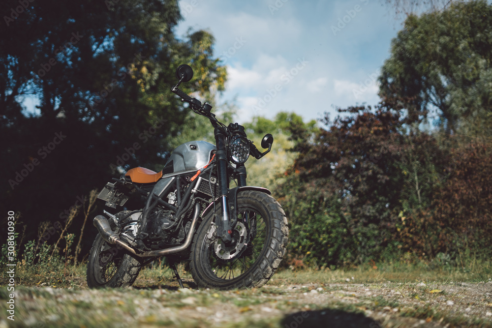 Cafe racer scrambler motorcycle, old fashioned vehicle with modern materials on forest background Cafe racer scrambler motorcycle, old fashioned vehicle with modern materials on forest background