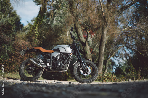 Cafe racer scrambler motorcycle, old fashioned vehicle with modern materials on forest background