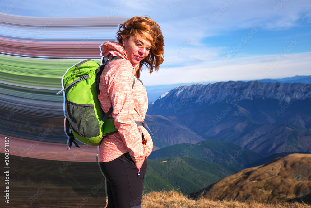 Mountain girl with pixel stretch effect at Iezer-Papusa mountains, Romania, with her hair in the wind and a big green backpack. Hiking concept.