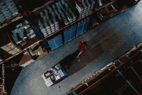 Strong worker on big warehouse. Lot of boxes at dark interior and top aerial view