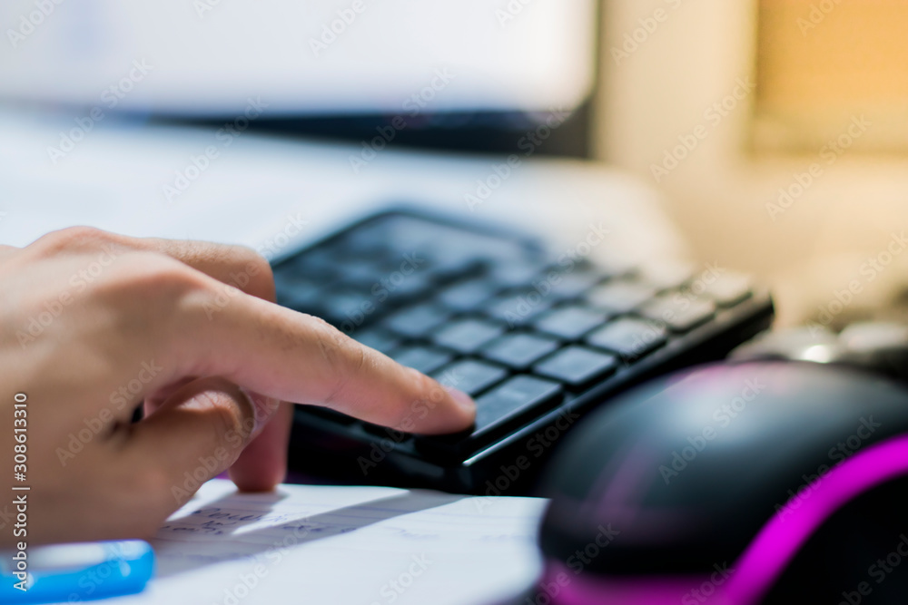 Fingers are pressing buttons on the black keyboard. Fingers are pressing buttons on the black keyboard.