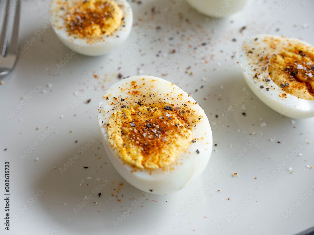 ฺBoiled egg topped with Cayenne pepper Pepper and Salt on a white dish,Egg colors white and yellow,Eat with bread ฺBoiled egg topped with Cayenne pepper Pepper and Salt on a white dish,Egg colors white and yellow,Eat with bread