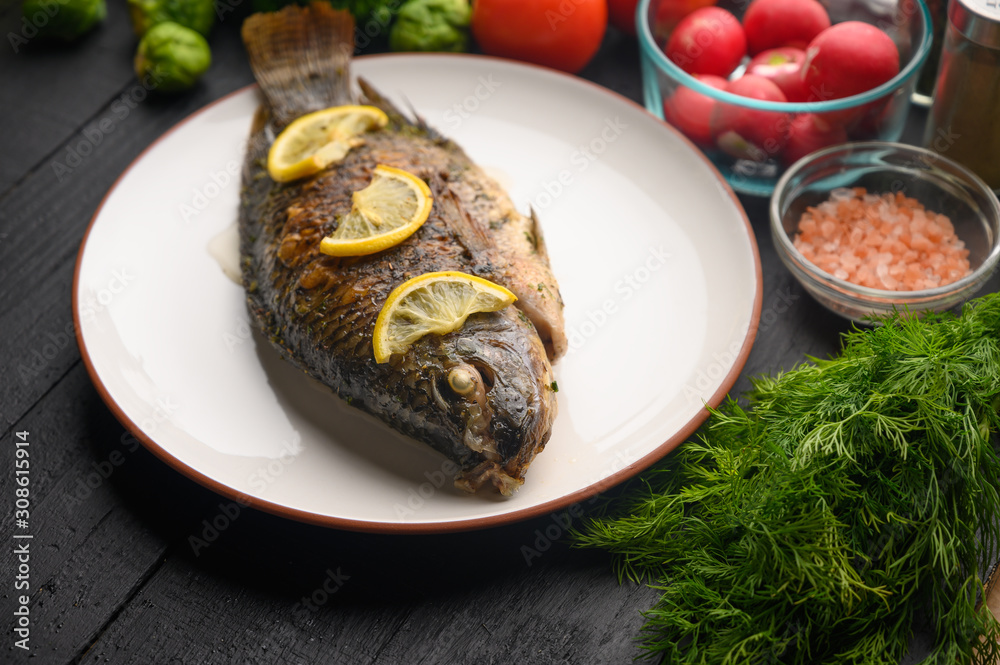Eastern or European cuisine, Fried fish with fresh vegetables, on a wooden black background. I also eat healthy food. Seafood, recipe book, selling fish, restaurant business