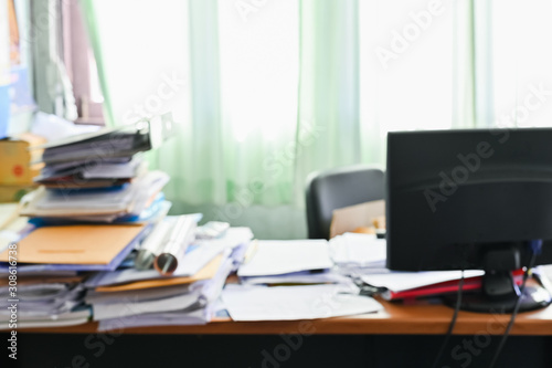 Blurred of Cluttered desk  full of documents A mess desk with many working stuff