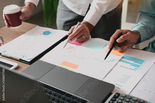 Business partnership pointing to the graph of the company financial statements report and profits earned during in the computer screen.