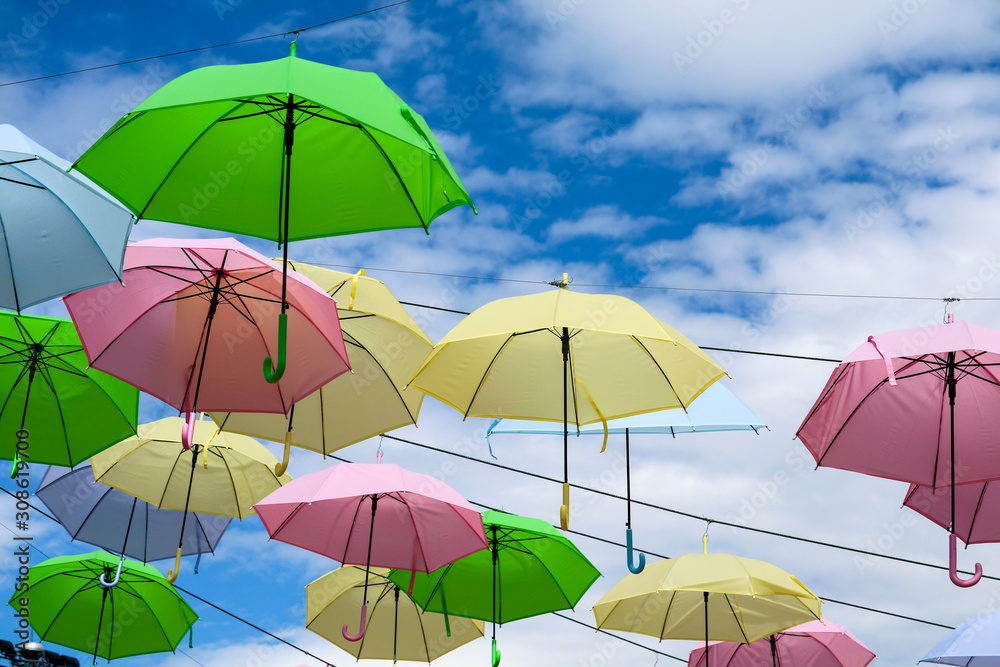 colorful fancy umbrella line decorate outdoor moving by wind on blue sky white cloud