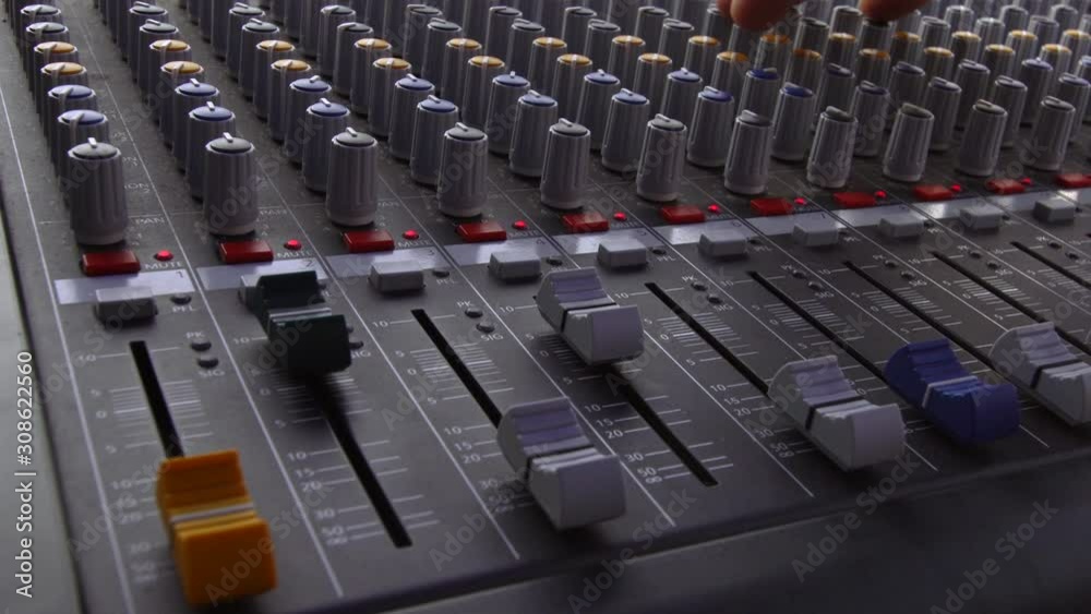 audio sound mixer, hand moving slides and knobs, music equipment