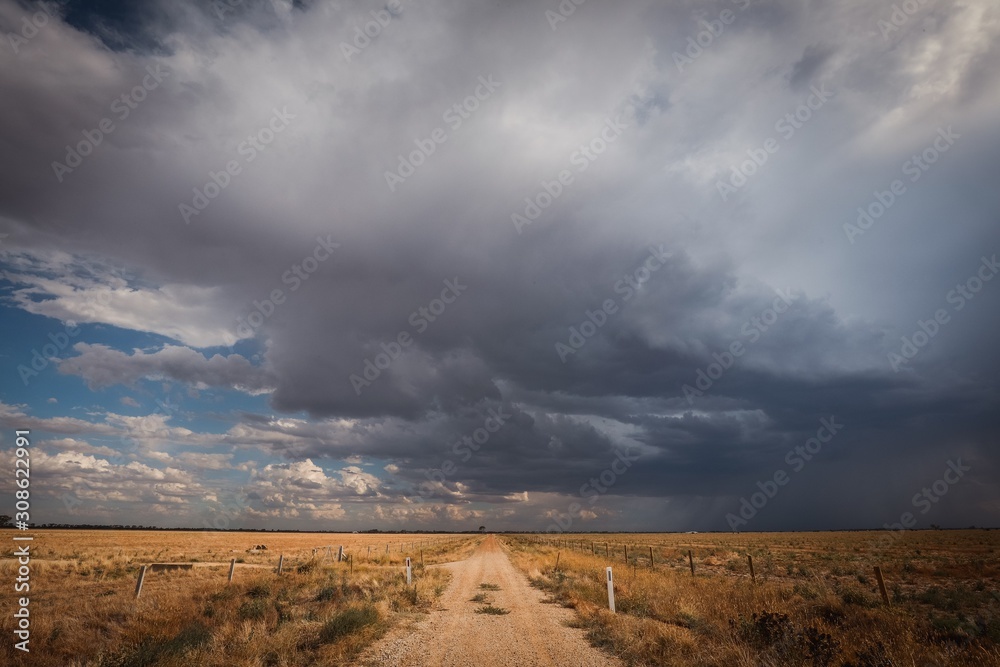 Storm on a country lane in remote central Victoria, Australia. Gravel road surrounded by dry paddocks in times of drought with the hopes of rain. Storm on a country lane in remote central Victoria, Australia. Gravel road surrounded by dry paddocks in times of drought with the hopes of rain.