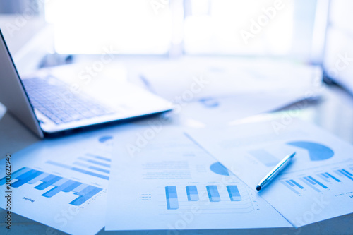 closeup of financial document with pen and laptop on desk at office