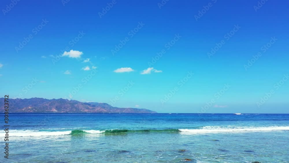 Paradise seascape with white waves foaming over rocky seabed on seashore of tropical island with light blue sky background in Bali, copy space Paradise seascape with white waves foaming over rocky seabed on seashore of tropical island with light blue sky background in Bali, copy space