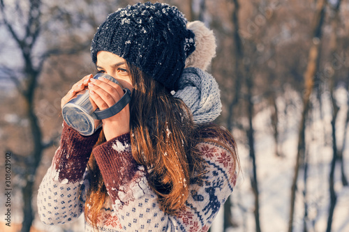 Photography Happy young woman with a cup of hot tea on snowy winter walk in nature