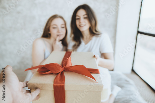 Young women receiving parcel from courier indoors. Parcel delivery, black friday sale, presents season