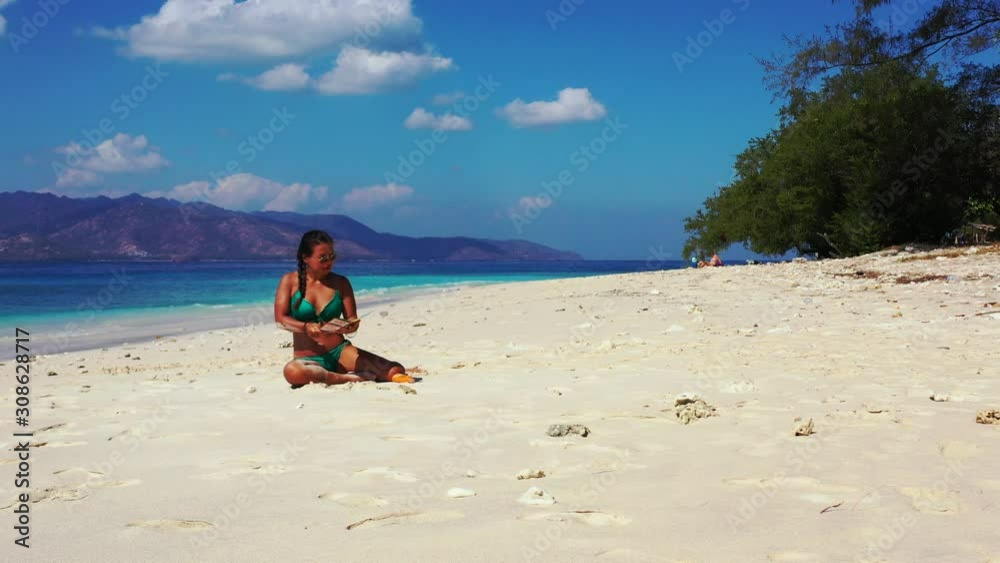 Bermuda islands, beautiful lady looking at the travel guide while relaxing in the white sand on the tropical beach Bermuda islands, beautiful lady looking at the travel guide while relaxing in the white sand on the tropical beach