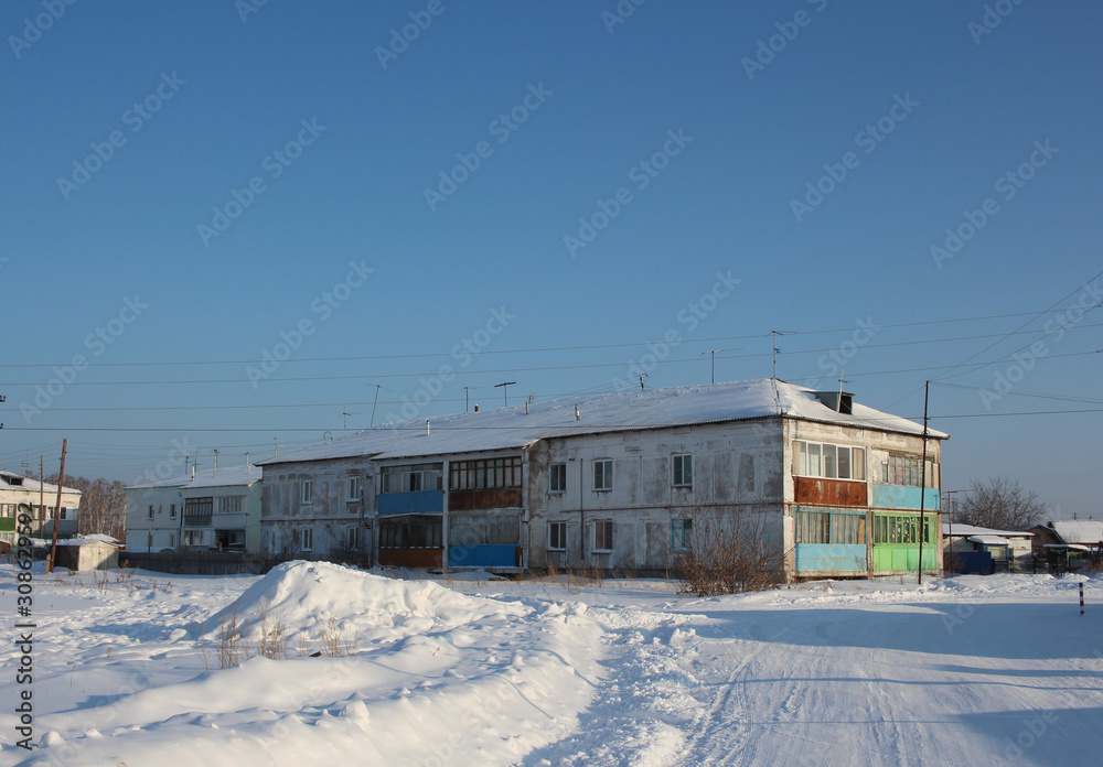 old two-storey house in a Siberian village in winter among the snow