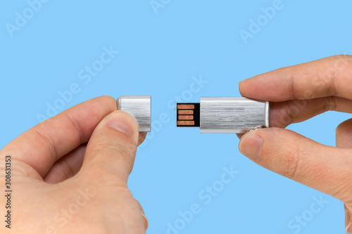 Gray USB memory stick on hand with blue background