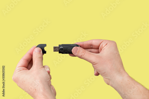 Black USB flash memory on hand with isolated yellow background